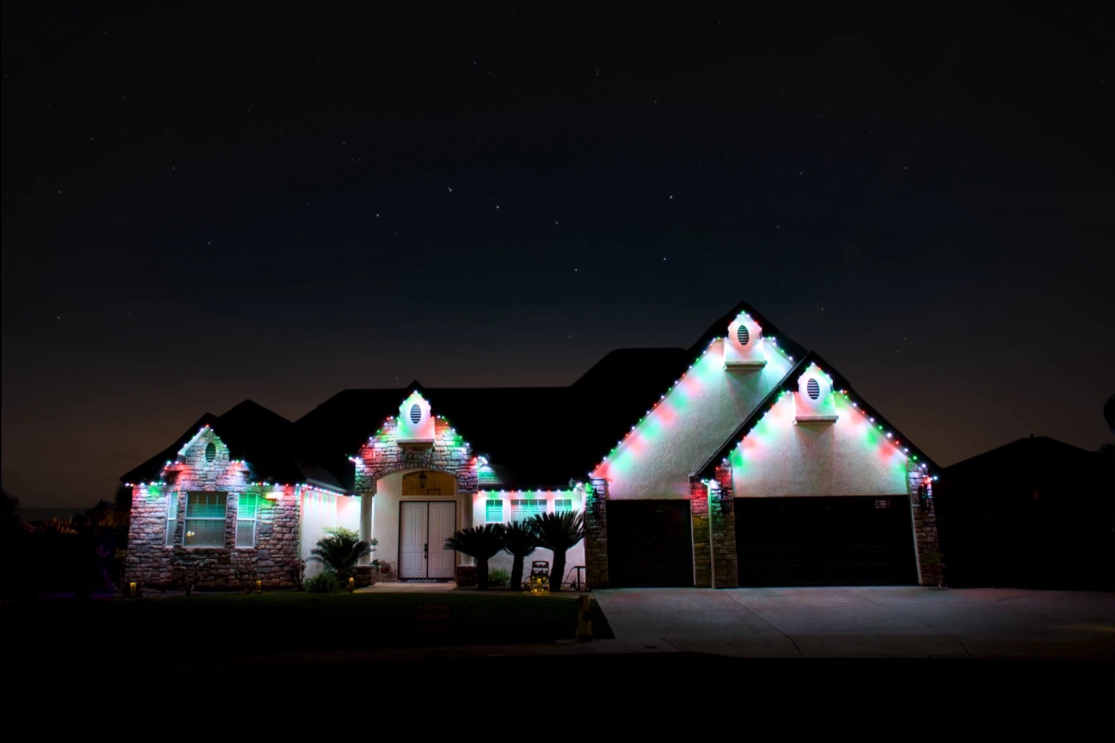 The same home with every roofline lit in an alternating red and green Christmas pattern
